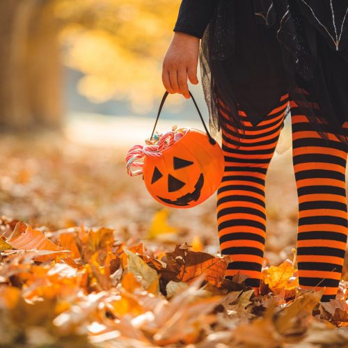 Little girl in witch costume having fun outdoors on Halloween trick or treat